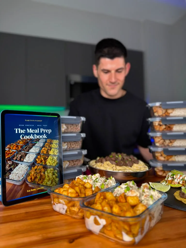 Chef behind a pan with stacked glass meal-prep containers and the cookbook on an iPad